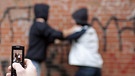 Zwei Jugendliche rangeln, ein dritter filmt mit dem Handy | Bild: picture-alliance/dpa