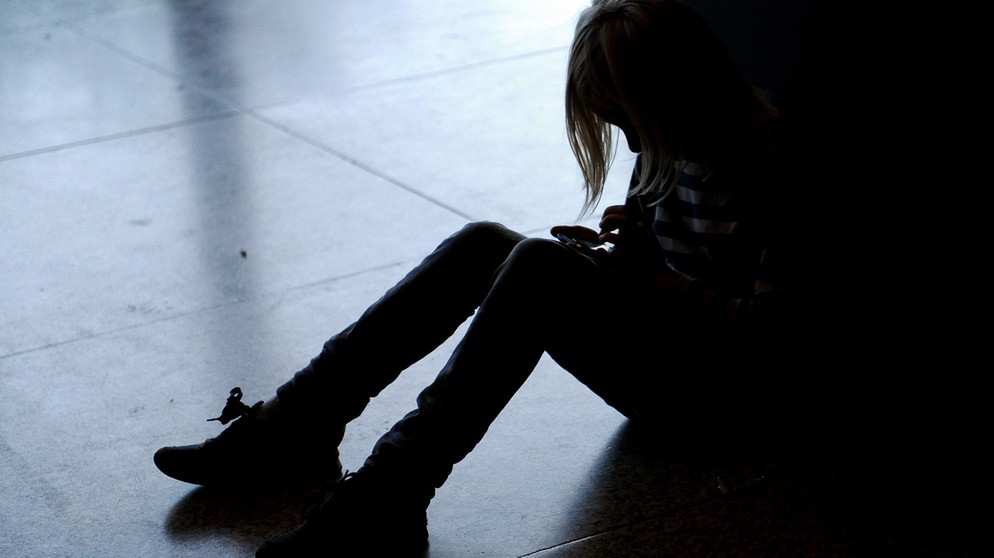 Mädchen sitzt mit gesenktem Kopf auf dem Fußboden | Bild: picture-alliance/dpa