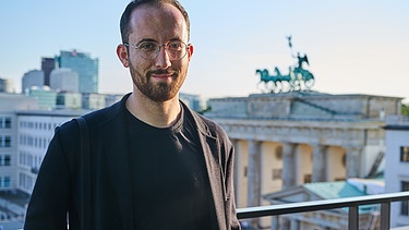 Igor Levit steht vor dem Brandenburger Tor auf der Terrasse des Allianz Forums. | Bild: picture alliance/dpa/ZB-Zentralbild | Annette Riedl
