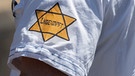 "Ungeimpft" steht auf einem nachgebildeten Judenstern am Arm eines Mannes, der versucht hatte, sich unter die Teilnehmer einer Demonstration zu mischen, die sich auch gegen Verschwörungstheorien zum Corona-Virus wendet | Bild: picture alliance/dpa | Boris Roessler