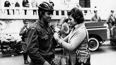 Eine Frau heftet am 25.04.1974 einem Soldaten in Lissabon, Portugal, eine rote Nelke an. Die rote Nelke ist das Symbol der portugiesischen Revolution. | Bild: picture-alliance / Telimprensa | Telimprensa