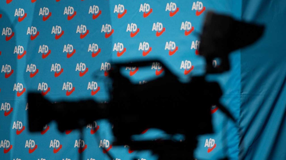 Eine Kamera und im Hintergrund eine Fototapete mit AFD-Logo (Symbolbild) | Bild: Bildrechte: picture alliance/Monika Skolimowska/dpa-Zentralbild/dpa