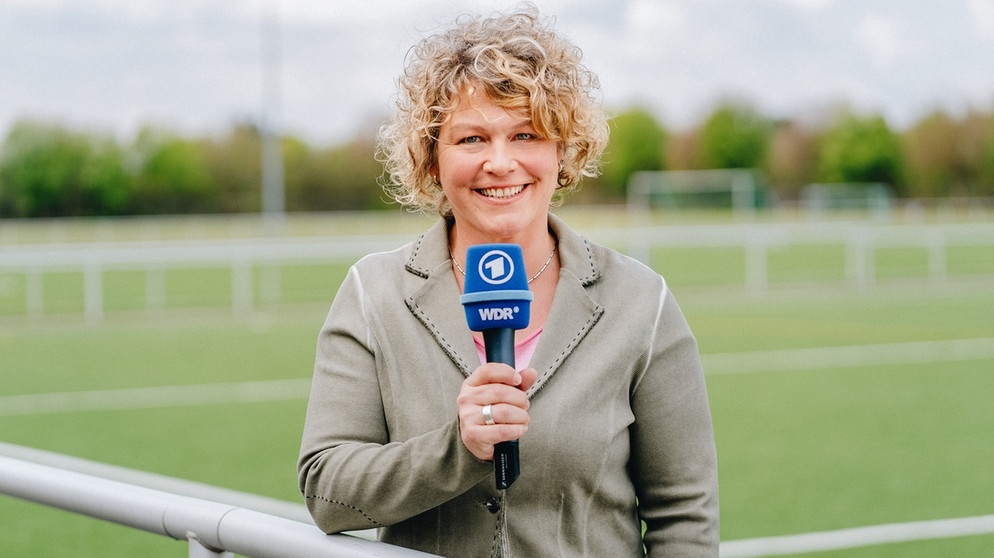 Julia Metzner, SWR-Hörfunk-Sportreporterin mit Mikrofon auf einem Fußballplatz | Bild: dpa-Bildfunk/Annika Fußwinkel