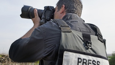 Fotograf mit "Presse"-Schriftzug auf dem Rücken seiner Jacke | Bild: picture alliance / Photoshot