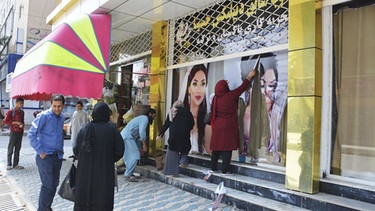 Arbeiter entfernen an einem Schönheitssalon in Kabul große Fotos von Frauen, nachdem die Taliban in die afghanische Hauptstadt eingedrungen sind | Bild: dpa-Bildfunk/-