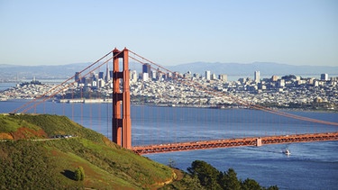 Die Golden Gate Bridge ist das unumstrittene Wahrzeichen und die wohl bekannteste Attraktion von San Francisco. 227 Meter ragen die beiden Brückentürme in die Höhe. Rund 120.000 Fahrzeuge befahren täglich die Brücke, die stadteinwärts mautpflichtig ist. Das 1937 für den Verkehr freigegebene Bauwerk verbindet die Stadt mit Marin County und dem Napa- und Sonoma-Valley auf der anderen Seite des Golden Gate in Kalifornien. Sechs Fahrspuren und zwei Geh- und Radwege brachten die Erbauer auf der Brücke unter, die als ein ingenieurtechnisches Meisterwerk gilt. Die Kosten beliefen sich auf 35 Millionen Dollar. Die von dicken Stahlkabeln gehaltene Hängebrücke misst 1.966 Meter, mit den Autobahnzufahrten sind es sogar 2.700 Meter.  | Bild: picture-alliance/dpa