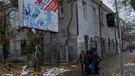 17.11.2022, Ukraine, Cherson: Anwohner stehen unter einer Plakatwand, an der die Überreste russischer Plakate hängen.  | Bild: dpa-Bildfunk/Bernat Armangue