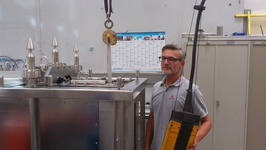 Christian Lang mit einer Spezialschere, die - ferngesteuert - im Reaktorbehälter unter Wasser stählerne Steuerelemente zerschneidet. | Bild: BR
