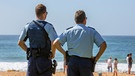 Polizisten mit Waffen am Strand von Palm Beach in Sydney.  | Bild: picture alliance / Loop Images | Martin Berry