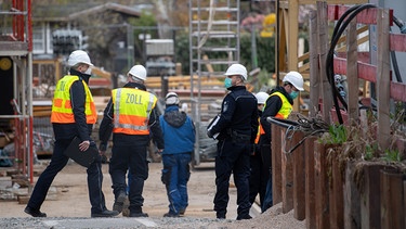 Mitarbeiter des Zolls führen auf einer Baustelle eine Durchsuchung im Zusammenhang mit Bekämpfung von Schwarzarbeit durch. | Bild: picture alliance/dpa | Sebastian Gollnow