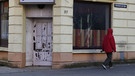 Bremen, Bremerhaven: Ein Mann geht an einem kaputten Fenster einer geschlossenen Kneipe entlang. Das komplette Haus ist unbewohnt.  | Bild: picture alliance/dpa | Carmen Jaspersen