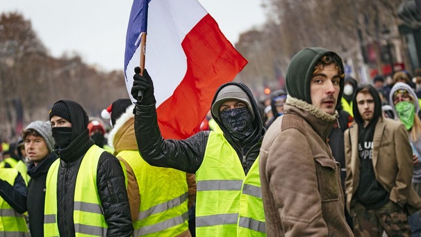 Demonstranten der "Gelbwesten" schwingen die französische Fahne bei einer Protestaktion in Paris  | Bild: dpa/picture-alliance/Christoph Hardt