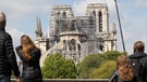 Frankreich, Paris: Ein Kran steht neben der Pariser Kathedrale Notre-Dame, die von Besuchern der Stadt betrachtet wird. Im April 2019 wurde die Kathedrale bei einem Brand schwer beschädigt. | Bild: dpa-Bildfunk/Marcel Kusch