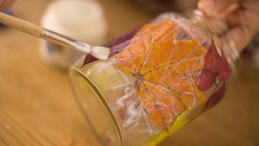 Serviettenkleber wird auf ein Marmeladenglas aufgetragen | Bild: BR