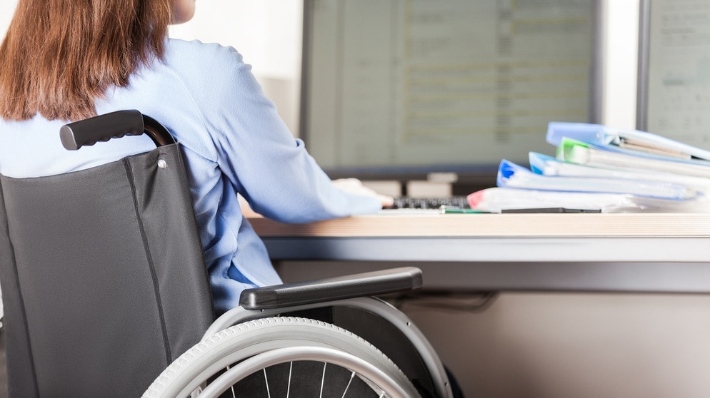 Eine Frau sitzt im Rollstuhl am Schreibtisch | Bild: colourbox.com
