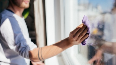 Ein Mann putzt die Glasscheibe eines Fensters | Bild: BR/Julia Müller