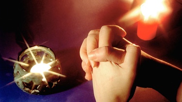 Gefaltete Hände und brennende Kerzen | Bild: picture-alliance/dpa