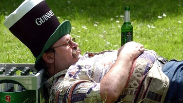 Mann liegt am Vatertag mit einer Bierkiste in einer Wiese | Bild: picture-alliance/dpa