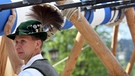 Ein Helfer aus einem örtlichen Verein stemmt einen 25 Meter hohen Maibaum per Muskelkraft in die Senkrechte. | Bild: picture-alliance/dpa