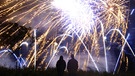 Passanten beobachten das Silvesterfeuerwerk | Bild: picture-alliance/dpa