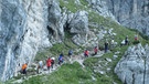 Mehrere Menschen wandern einen Berg hinauf. | Bild: Helmut Betz