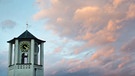 Ein Kirchturm ist am 24.12.2014 in Stuttgart (Baden-Württemberg) vor den von der Abendsonne angestrahlten Wolken zu sehen. | Bild: Daniel Naupold/dpa