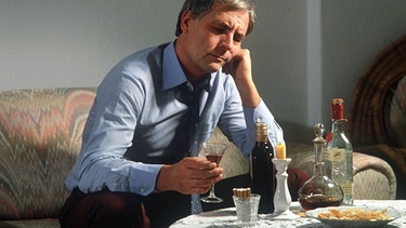 Mann sitzt alleine zuhause und trinkt | Bild: picture-alliance/dpa