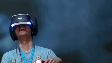 Ein Fachbesucher testet auf der Spielemesse Gamescom mit einer VR-Brille (Virtual Reality) von Sony das Computerspiel Batman.  | Bild: picture-alliance/dpa