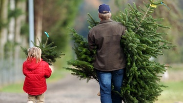 Vater und Tochter nach dem Kauf von zwei Tannenbäumen | Bild: picture-alliance/dpa