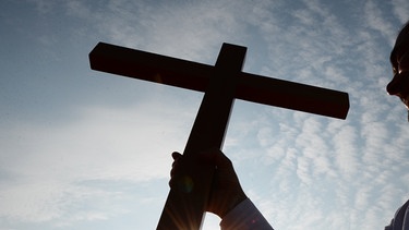 Pfarrer hält Kreuz im Gegenlicht | Bild: picture-alliance/dpa