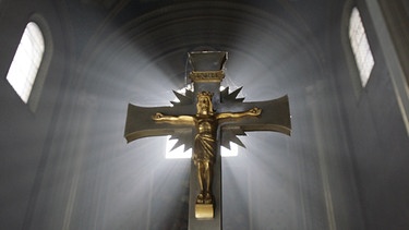 Kreuz vor erleuchtetem Kirchenfenster | Bild: picture-alliance/dpa