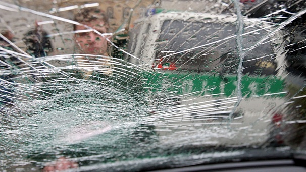 Polizeiwagen hinter einer zersplitterten Scheibe | Bild: picture-alliance/dpa