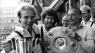 Die Bayern-Spieler Karl-Heinz Rummenigge (l) und Paul Breitner (M) sowie Trainer Pal Csernai (r) präsentieren am 13.6.1981 auf dem Balkon des Münchner Rathauses gutgelaunt die Meisterschale.  | Bild: picture-alliance/dpa