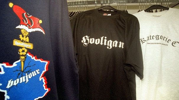 Bedruckte T-Shirts mit den Schriftzügen "Hooligan", "Kategorie C" und einem in die Landkarte Frankreichs enschlagenden Fahnenmast in einem Sportgeschäft in der Münchner Innenstadt  (29.06.1998) | Bild: picture-alliance/dpa
