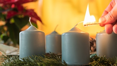 Adventskranz - eine Person zündet eine Kerze an. | Bild: colourbox.com
