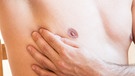 Ein Mann untersucht seine Brust, denn auch Männer können an Brustkrebs erkranken, wenn auch viel seltener als Frauen. | Bild: picture alliance / dpa Themendienst