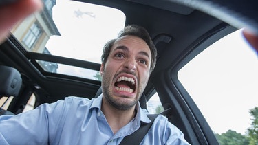 Mann am Steuer, der vor Wut schreit: Auch im Straßenverkehr geht es bei hohen Temperaturen hitziger zu | Bild: pa/dpa/Christin Klose