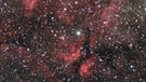 Milchstraße im Sternbild Schwan. In der Mitte der Stern Sadir (Gamma Cygni), umgeben vom roten Gamma-Cygni-Nebel IC 1318. In Wirklichkeit ist Sadir auf halbem Wege zwischen uns und dem Nebel, der über 3.000 Lichtjahre von der Erde entfernt ist. | Bild: P. Christoph Gerhard