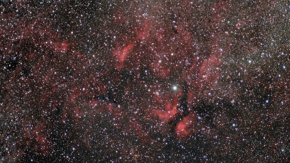 Milchstraße im Sternbild Schwan. In der Mitte der Stern Sadir (Gamma Cygni), umgeben vom roten Gamma-Cygni-Nebel IC 1318. In Wirklichkeit ist Sadir auf halbem Wege zwischen uns und dem Nebel, der über 3.000 Lichtjahre von der Erde entfernt ist. | Bild: P. Christoph Gerhard