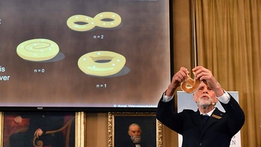 Professor Thors Hans Hansson erklärt die Forschung der diesjährigen Nobel-Preisträger mit Brezeln und Donuts. | Bild: dpa-Bildfunk