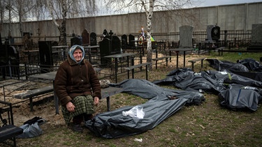 12.04.2022, Ukraine, Kiew: *** ATTENTION EDITORS GRAPHIC CONTENT ***
Nadija Trubtschaninowa, sitzt auf einem Friedhof neben einem Plastiksack, der die Leiche ihres Sohnes Wadym Trubtschaninow enthält, nachdem er am 30. 03.2022 von russischen Soldaten in Butscha getötet wurde. Foto: Rodrigo Abd/AP/dpa - *** ATTENTION EDITORS GRAPHIC CONTENT *** +++ dpa-Bildfunk +++ | Bild: dpa-Bildfunk/Rodrigo Abd