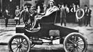 Der 37jährige Henry Ford posiert im Jahr 1900 vor seinem Werk in Detroit (Michigan) am Lenkrad eines brandneuen Autos | Bild: picture-alliance / dpa