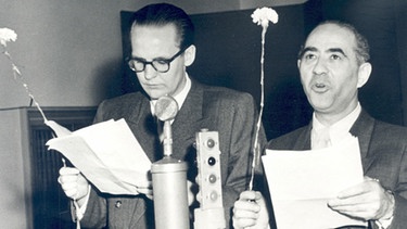 Helmuth M. Backhaus (links) mit Fritz Benscher mit Manuskript und Nelke in der Radiosendung „Die traurige Ballade“, ca. 1948. Kabarettsatire war ein Markenzeichen von Benscher.
| Bild: BR, Historisches Archiv, Lindinger