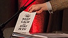 Martin Fogt zeigt lächelnd ein Mini-Plakat mit der Aufschrift "Keep calm and stay in EU" | Bild: BR/Andreas Dirscherl