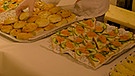 Eine Köchin serviert selbstgemachte Häppchen und Teigwaren | Bild: Synagoge Augsburg / korro