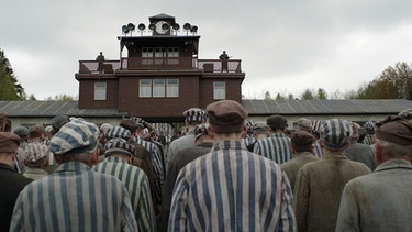 KZ-Häftlinge in gestreifter Kluft stehen beim Appell auf dem Hof | Bild: MDR/BR/UFA Fiction