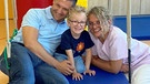 Bei der Bewegungstherapie: Tobias (mi.) mit seinem Vater (li.) und Physiotherapeutin Katharina Nirmaier (re.)  | Bild: Kinderkrankenhaus St. Marien gGmbH