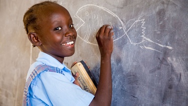 Eine Schülerin in Kenia schreibt an die Tafel | Bild: Hilfsverein Nymphenburg