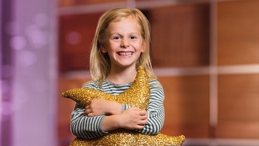 Kleines Mädchen mit Sternstunden-Stern als Kissen im Arm | Bild: BR/Lisa Hinder