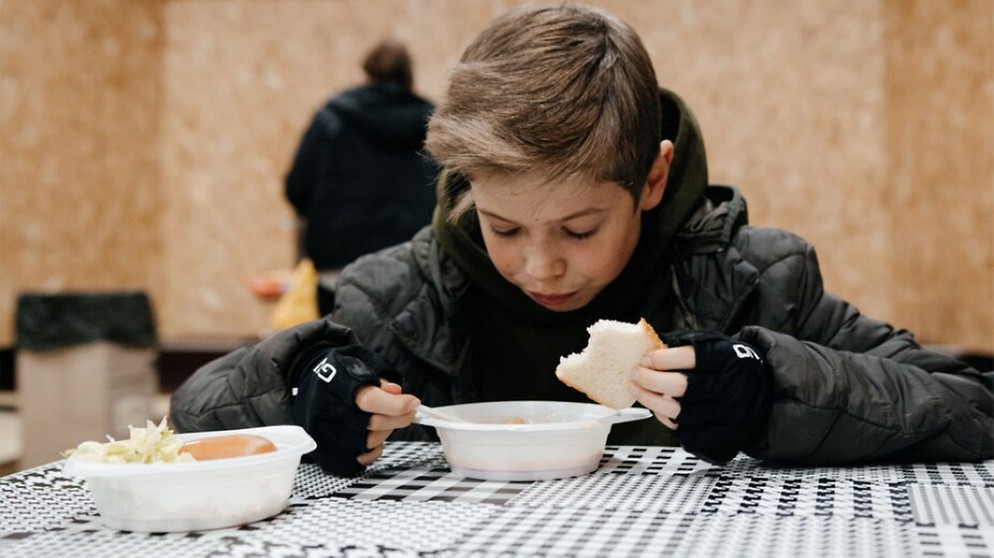 Ein hungriger Junge erhält im Znamianka eine warme Mahlzeit. | Bild: Straßenkinder e.V.